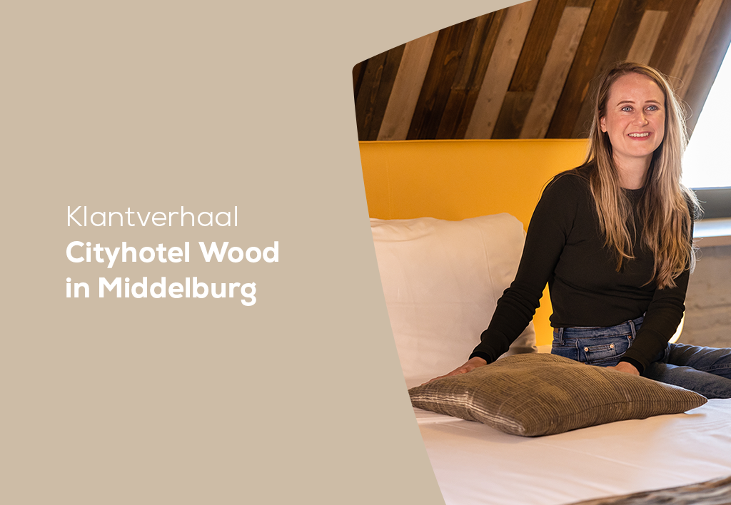 Hotelmanager Eva van de Parel van Cityhotel Wood zittend op een bed in een van de hotelkamers in Wood.