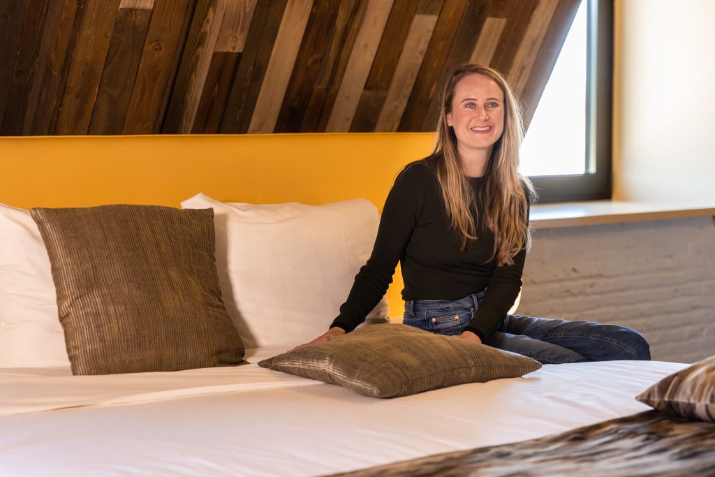 Hotelmanager Eva van de Parel van Cityhotel Wood zittend op het bed in een van de kamers van het hotel.